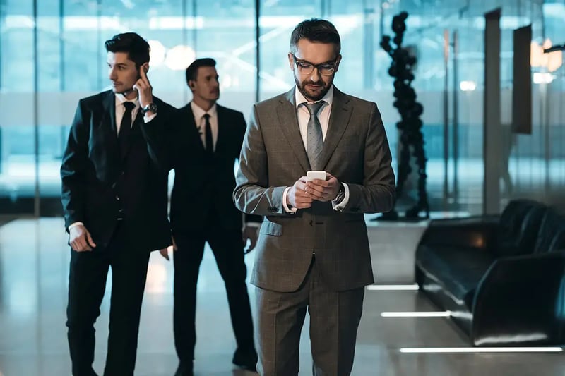 Two close security professionals stand near an executive