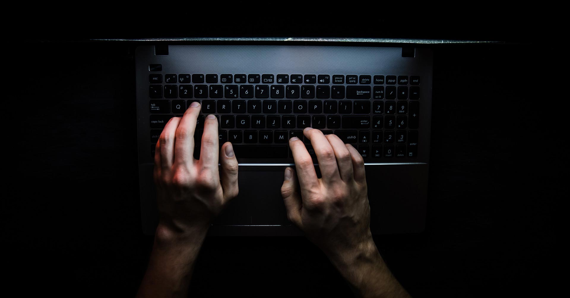 Overhead view of hands typing on a laptop keyboard