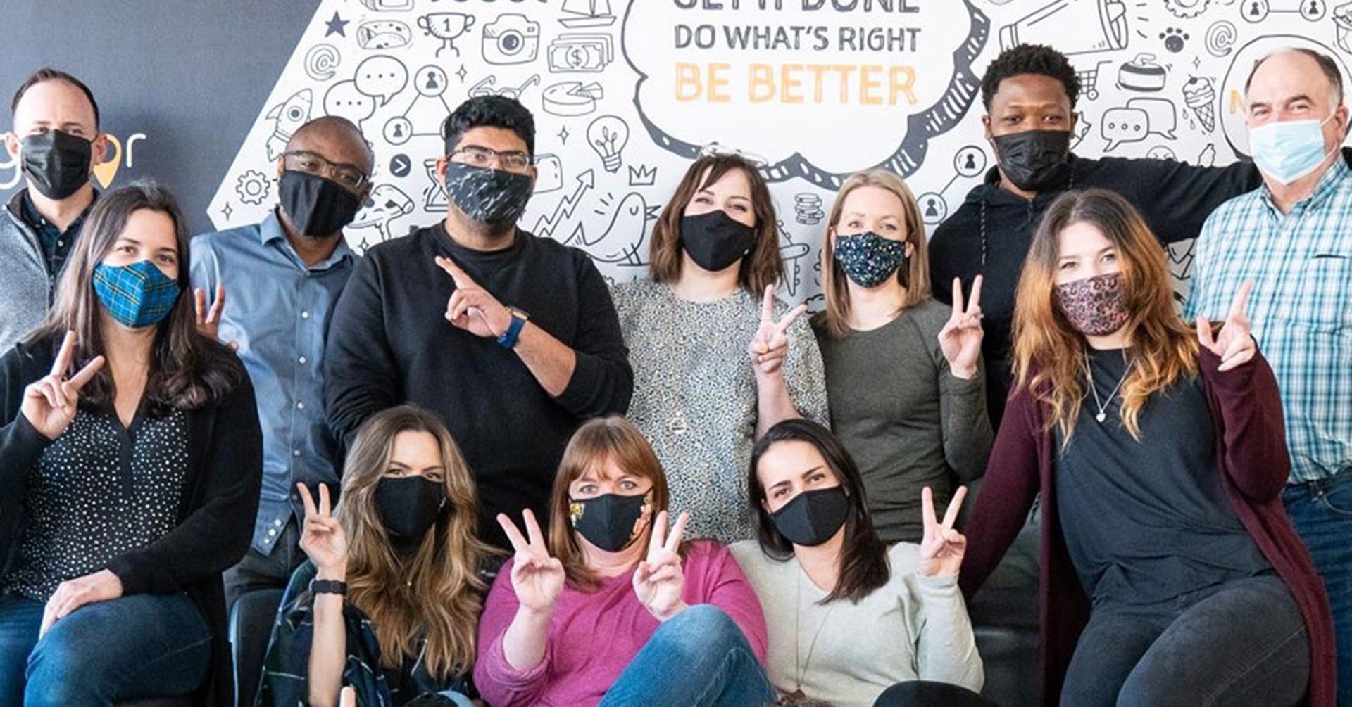 A  group of LifeRaft employees in front of a mural in their Hafliax, Nova Scotia office.