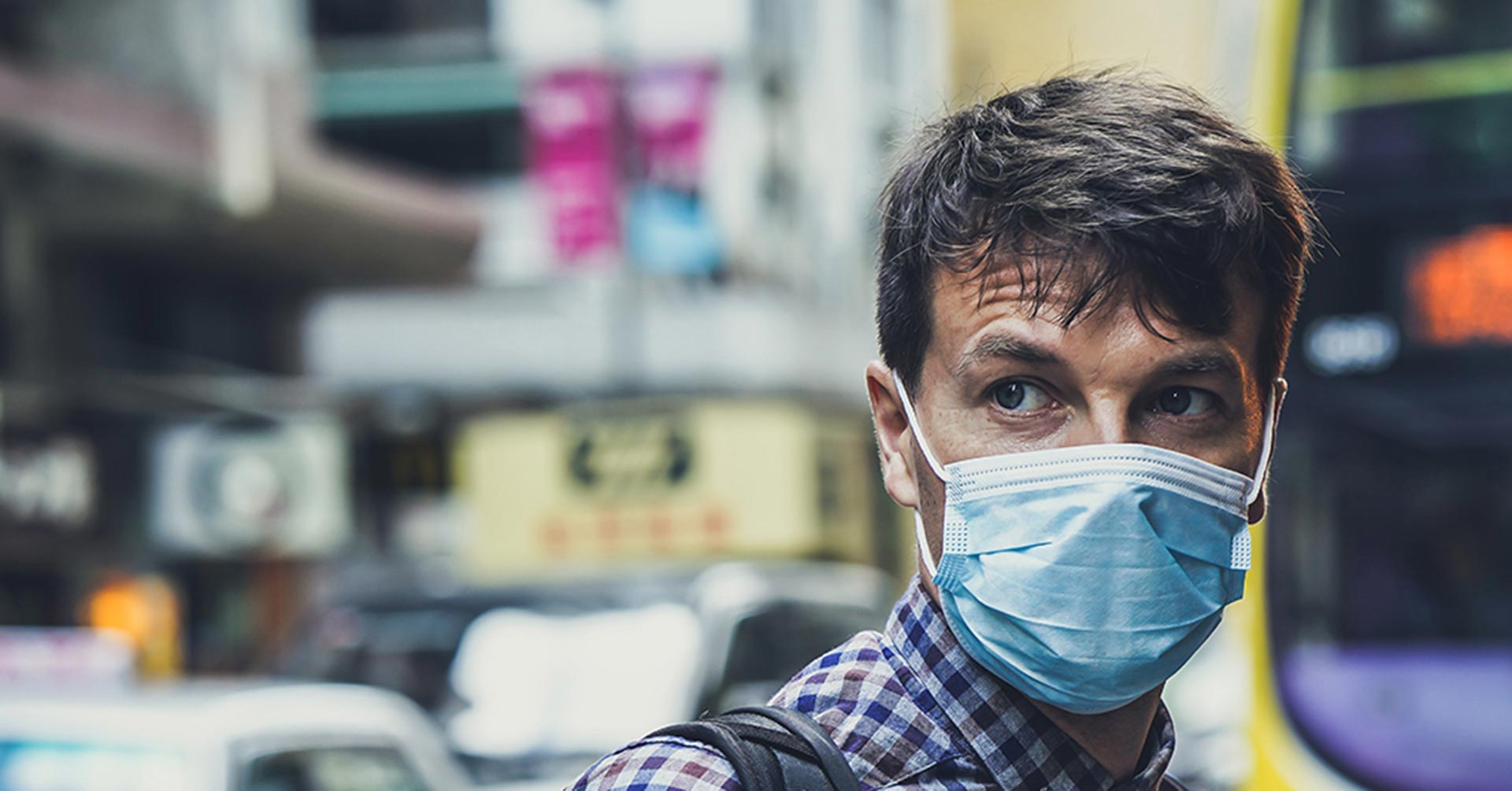 A man on a city street wearing a medical mask during the COVID-19 pandemic