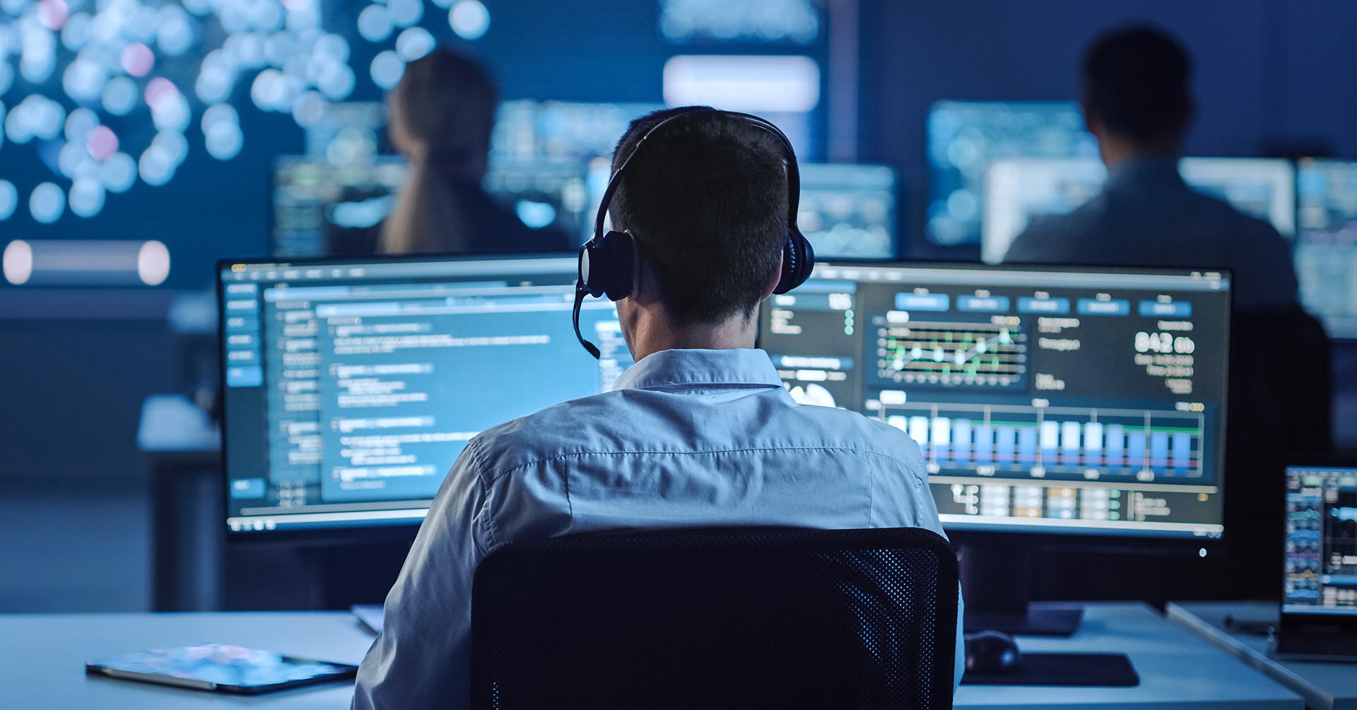 A security professional working at a computer station in a GSOC