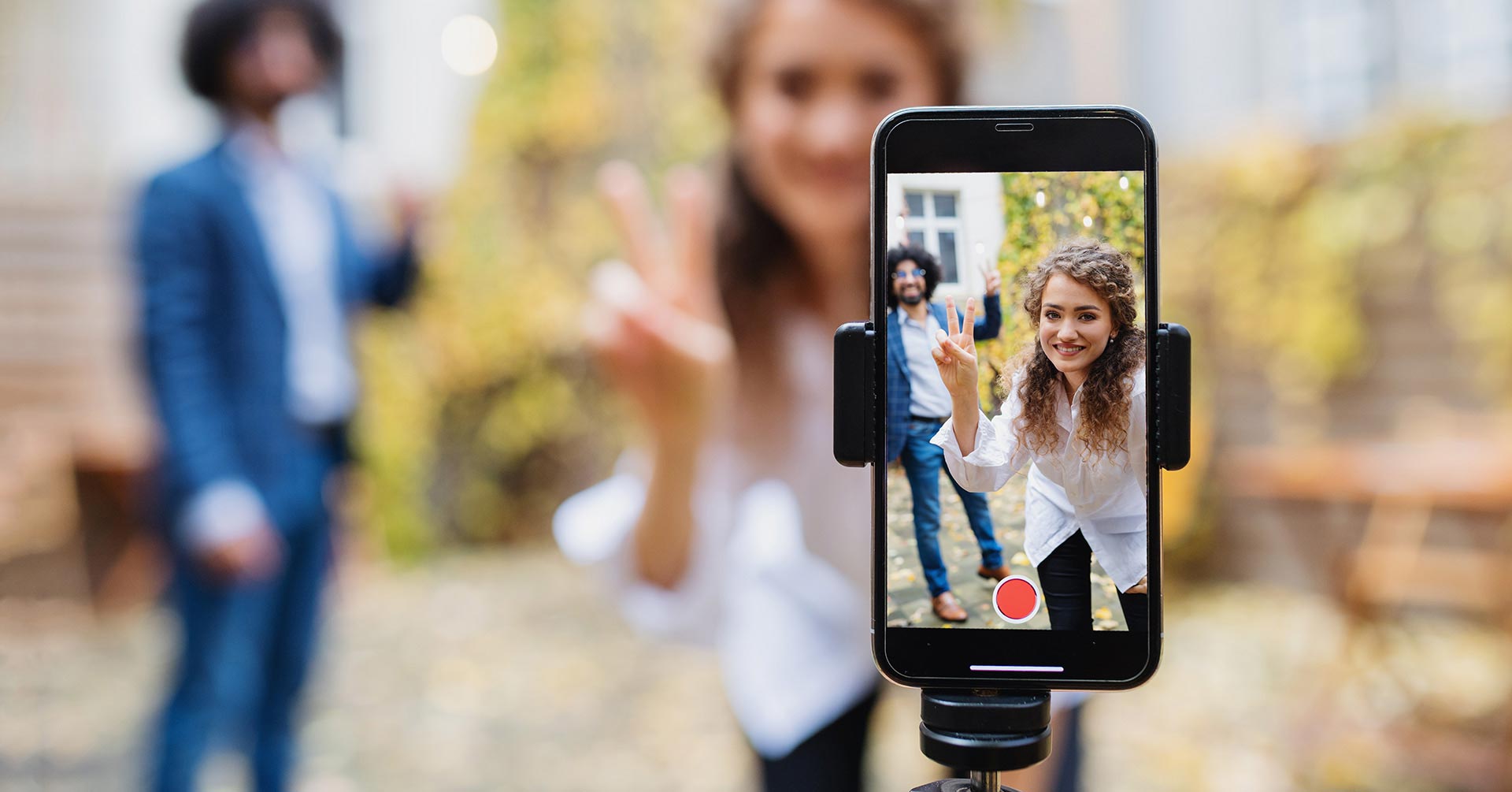 Two social media influencers recording a video on their mobile device