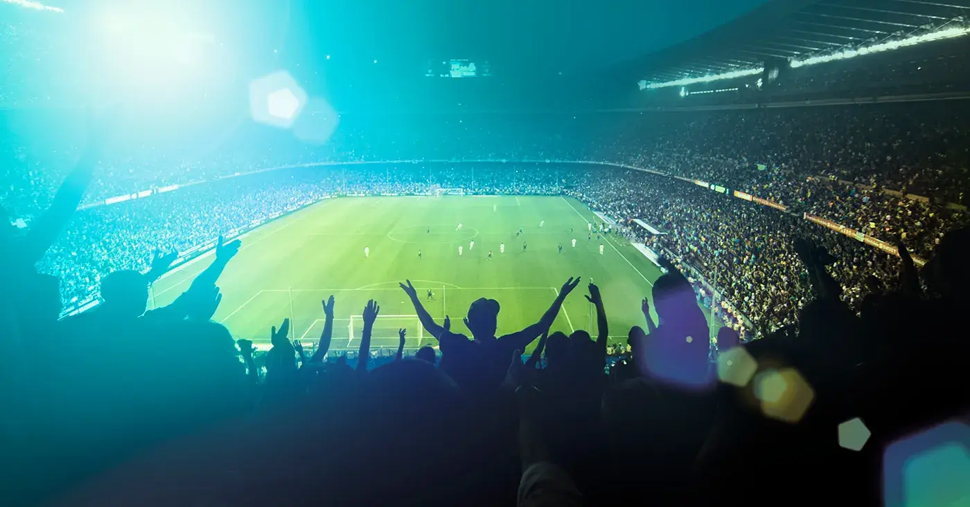 Crowd of soccer fans cheering in a packed stadium, highlighting the scale and security challenges of major event operations.