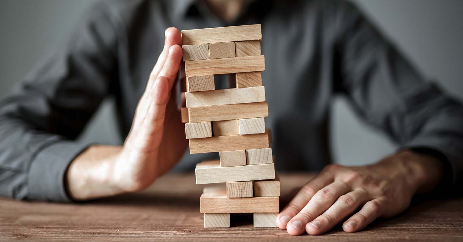 Person holds wood blocks from falling. Managing risk concept, plan and strategy. 