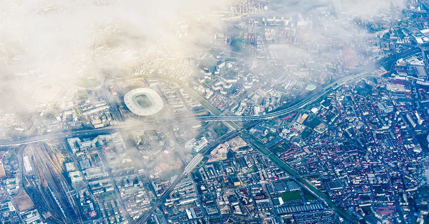 Aerial view of the Stade de France in Saint-Denis, near Paris, surrounded by transportation networks and urban infrastructure, highlighting the complexities of major event security.