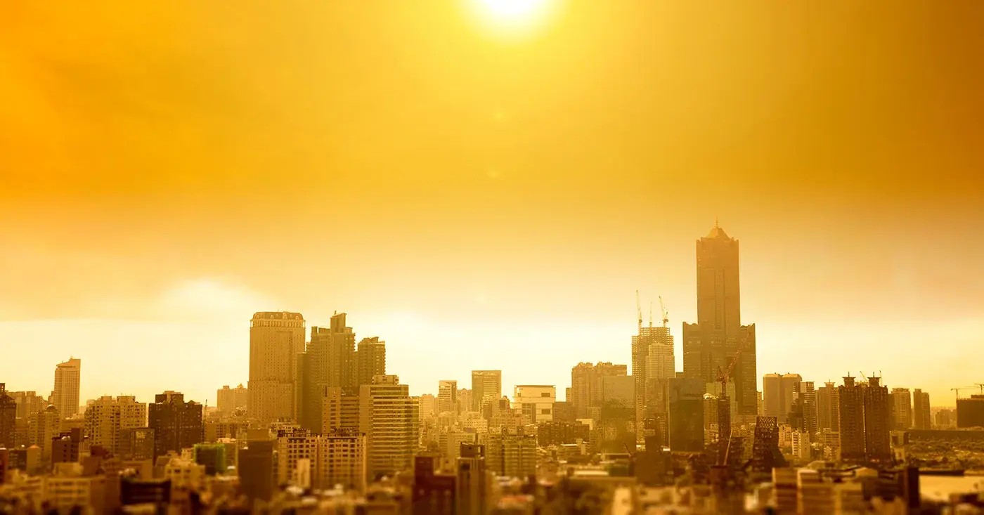City skyline under intense golden sunlight, representing extreme summer heat and rising duty of care risks for traveling employees.