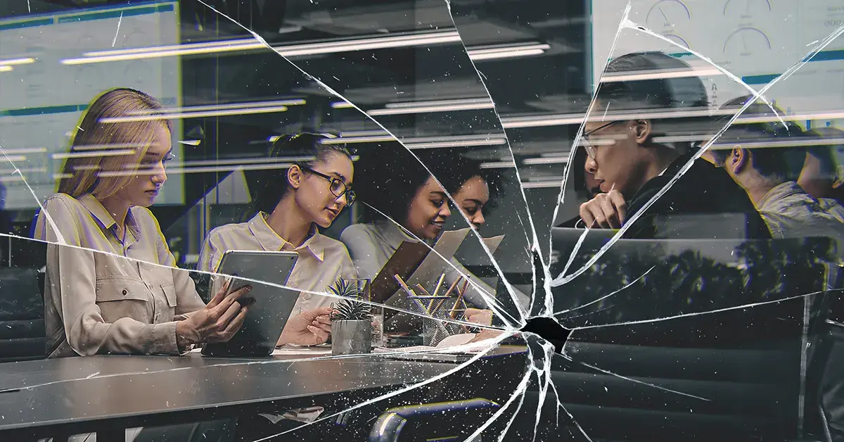 Office team collaborating at night with a cracked glass overlay, symbolizing workplace violence risk and the need for proactive prevention and safety planning
